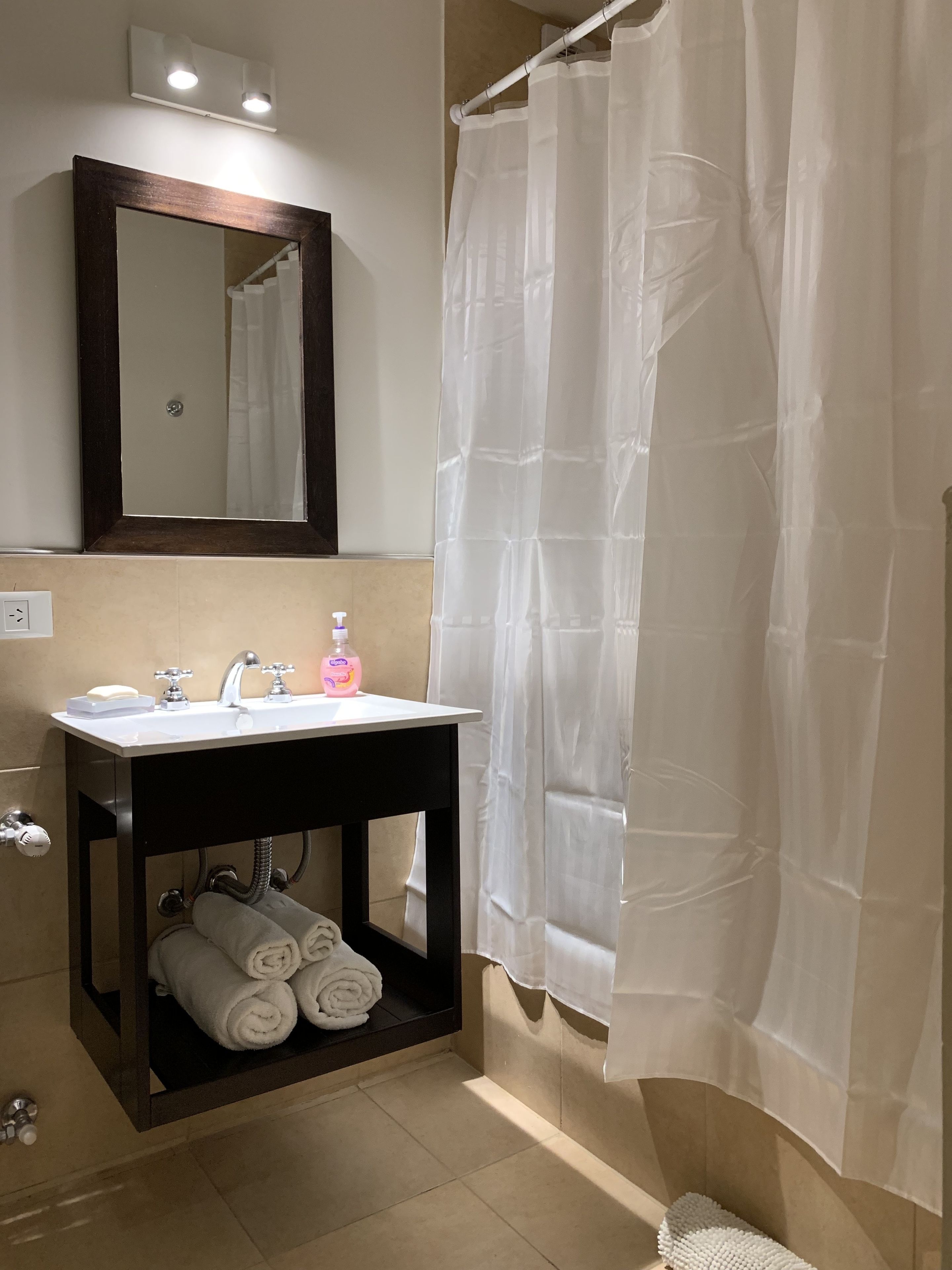 A bathroom with a sink, mirror, and shower curtain.