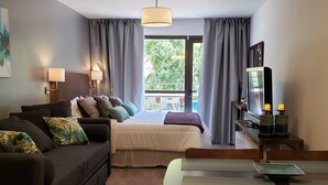 A modern hotel room with a sofa, a bed, a dining table, and a TV. - Urbana Suites & Studios 440 (San Carlos de Bariloche)
