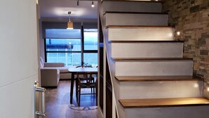 A modern interior with a staircase, a dining area, and a view of the sea. - Urbana Suites & Studios 440 (San Carlos de Bariloche)