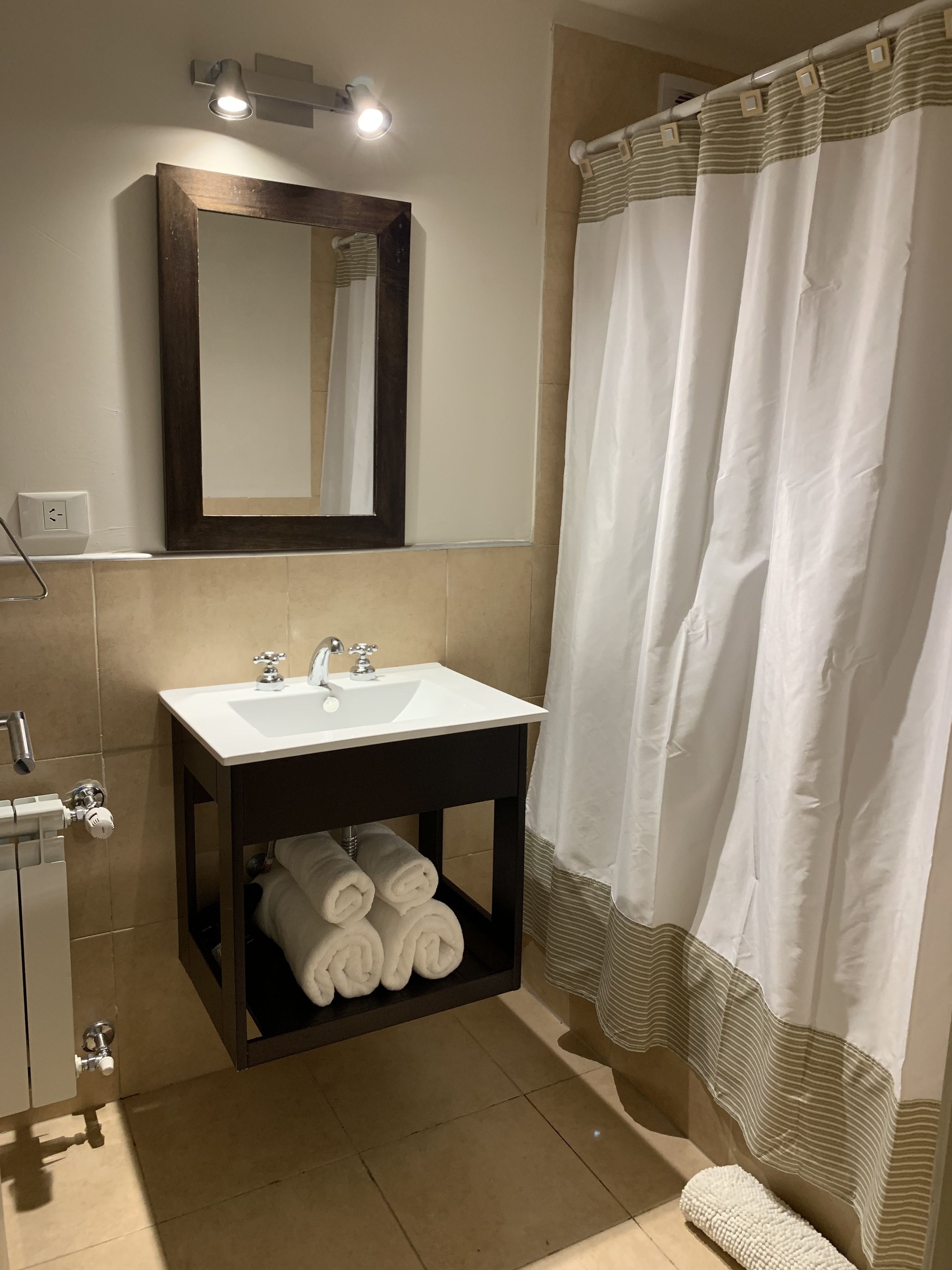 Une salle de bain avec un lavabo blanc, un miroir et un rideau de douche.