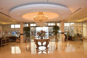 A spacious lobby with a large chandelier, a reception desk, and a round table with flowers. - Mandarin Al Shamal Hotel Apartments (Riyadh)