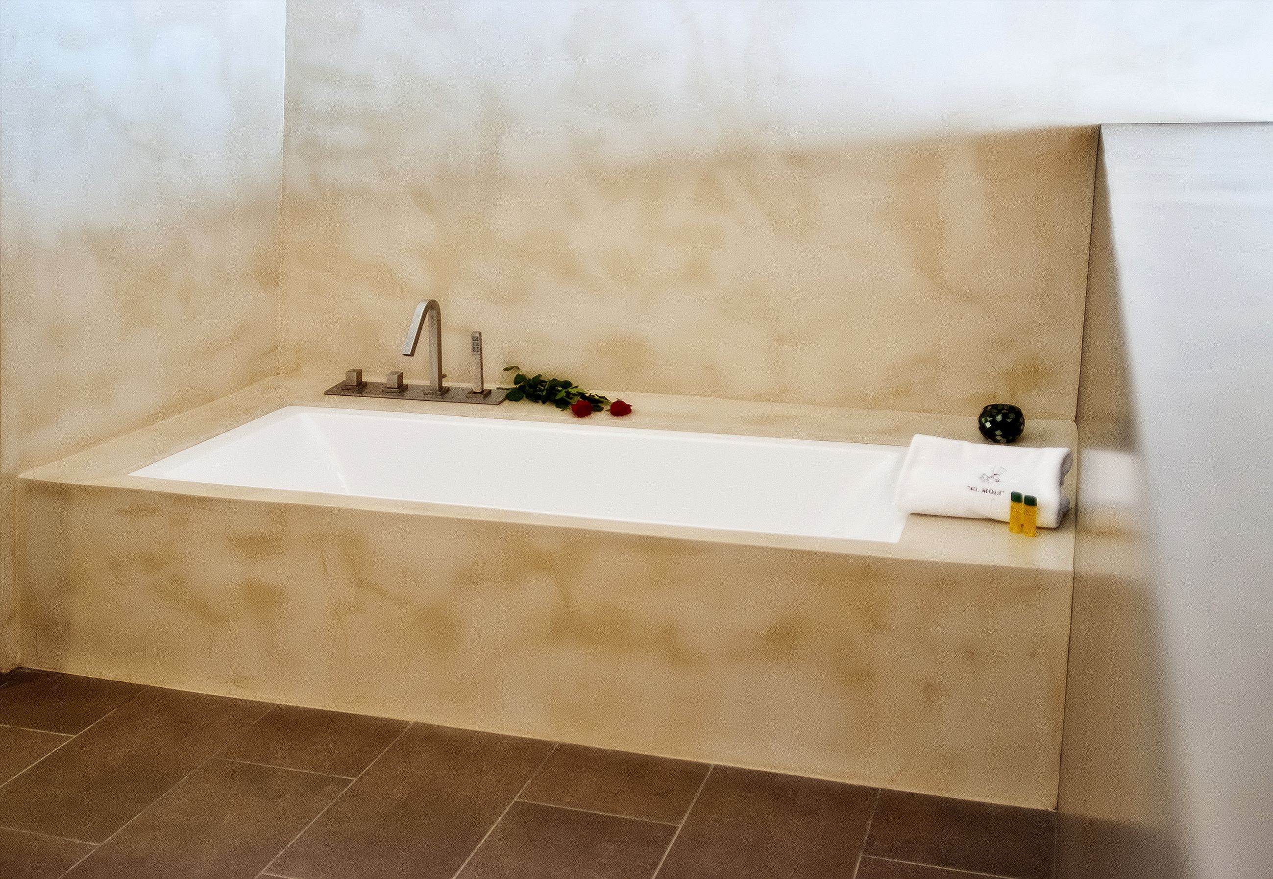 A bathtub with a towel and a rose.