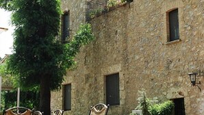 A stone building with a courtyard, outdoor seating, and potted plants. - Hotel Restaurant el Molí (Pont de Molins)
