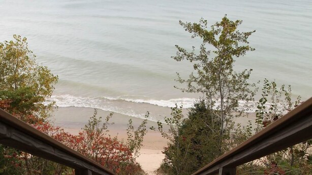 A wooden staircase leading to a beach with a view of the ocean.