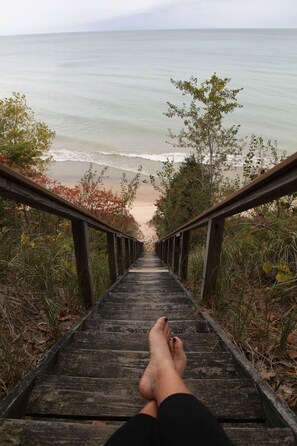 Un escalier en bois menant à une plage d’où l’on a une vue sur l’océan.