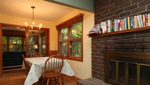 A dining area with a table set for four, a fireplace, and a bookshelf filled with books.
