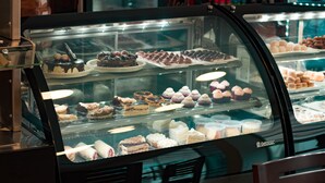 En bagerdisk fyldt med forskellige kager og desserter.