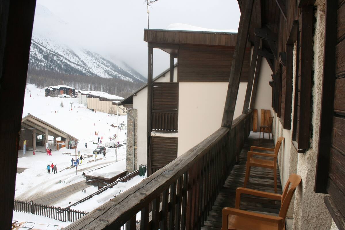 Un balcon en bois offrant une vue sur une montagne enneigée et une station de ski.