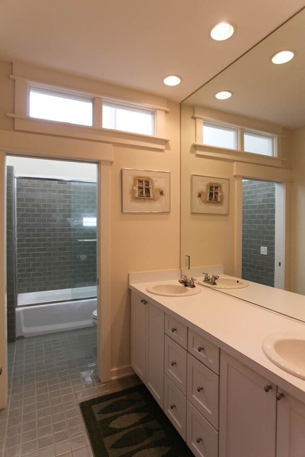 A bathroom with two sinks, a large mirror, and a shower area.