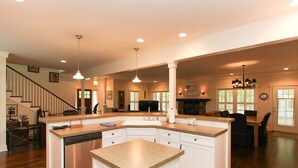 A spacious kitchen with a large island, wooden flooring, and pendant lighting. - Douglas Manor (Douglas)