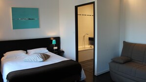 Une chambre d’hôtel comprenant un lit, une table de chevet avec une lampe, un canapé et une salle de bain avec une baignoire.