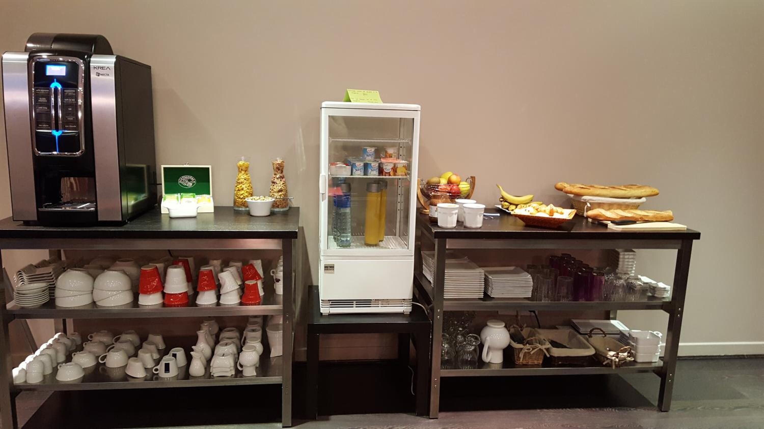 Eine Küchenzeile mit Kaffeemaschine, Kühlschrank und einem Buffet mit Speisen und Getränken.