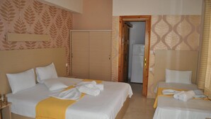A hotel room with two beds, each with white linens and a yellow throw blanket. There is a wooden headboard on one bed and a plain headboard on the other. A wooden wardrobe is visible in the background.
