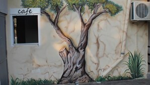 A mural of a tree on a building wall with a cafe sign above it.