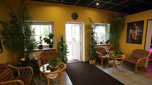 A room with wicker furniture, potted plants, and a clock on the wall.
