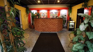 A reception area with a brick counter, potted plants, and a vending machine.