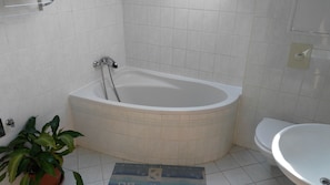 A bathroom with a bathtub, toilet, and a potted plant. - Penzion Exotic (Ostrava)