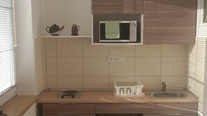 A compact kitchen with a microwave, sink, and a small dining area with a chair.