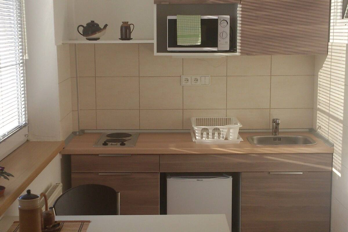 Une cuisine compacte équipée d’un four à micro-ondes, d’un évier et d’un petit coin repas avec une chaise.