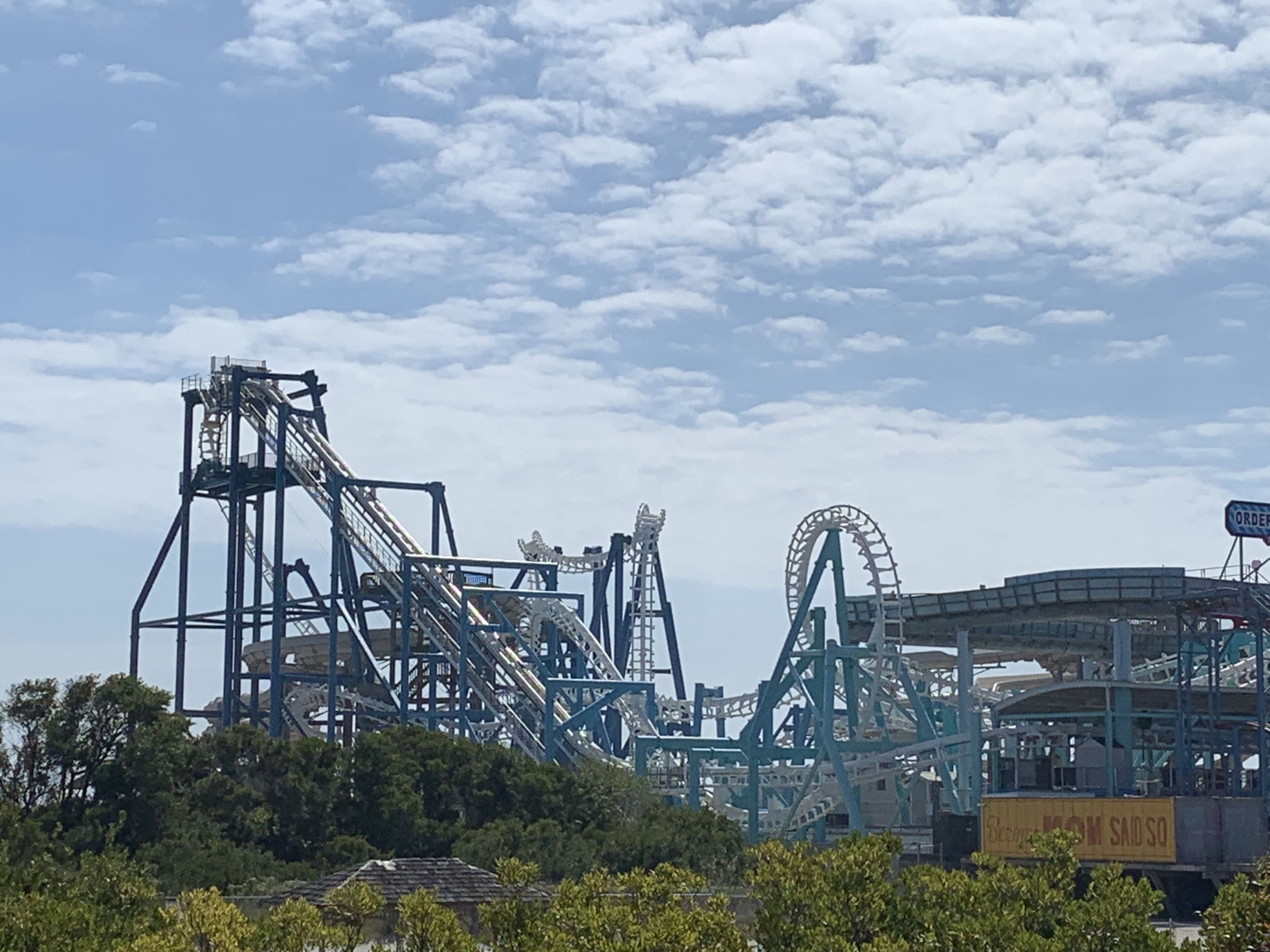 A roller coaster with a tall structure and a circular track, surrounded by trees and a clear sky.