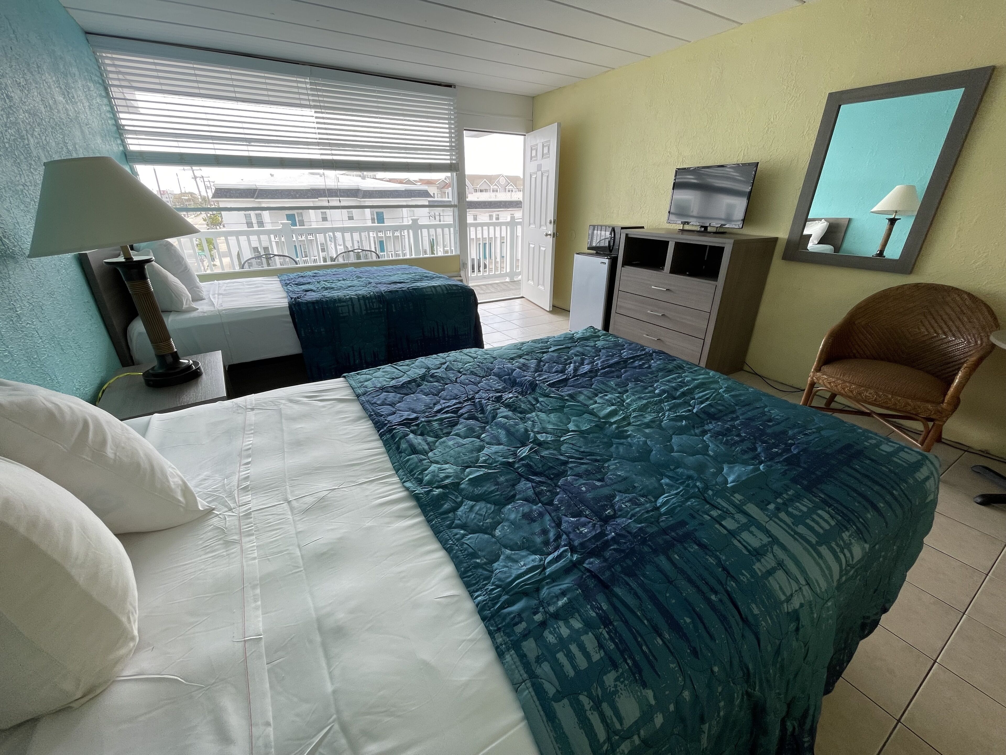 A hotel room with a bed, a desk, a chair, a TV, and a window with blinds.