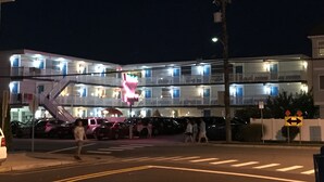 A multi-story hotel with balconies, a staircase, and a neon sign. - Bird Of Paradise Motel (North Wildwood)