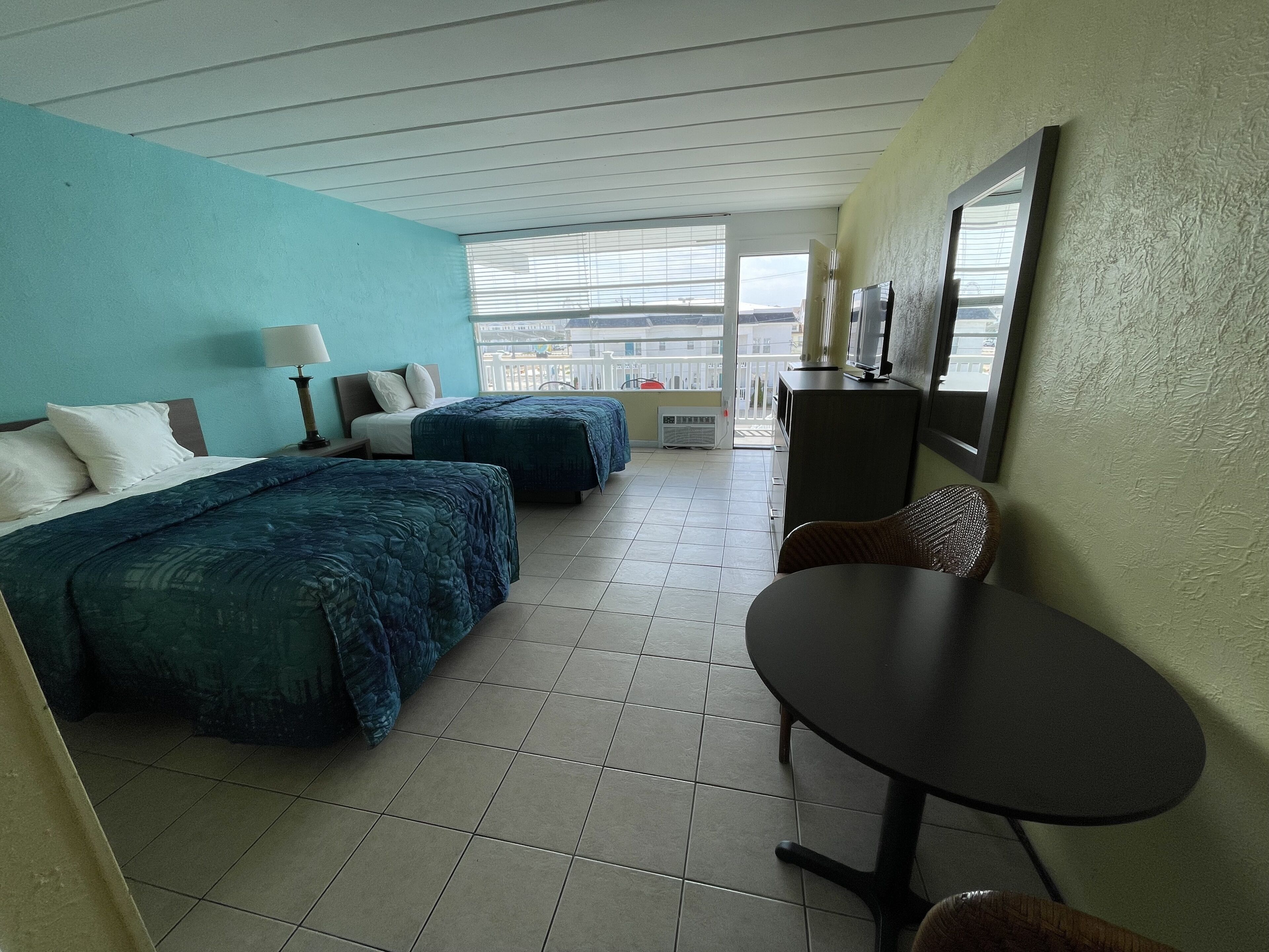 A hotel room with two beds, a desk, and a chair.