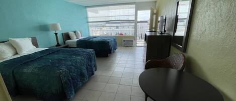 A hotel room with two beds, a desk, and a chair.