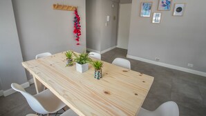 Ein moderner Essbereich mit einem Holztisch, weißen Stühlen und Topfpflanzen.