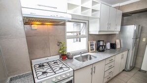 Eine moderne Küche mit Gasherd, Edelstahlgeräten und einer Arbeitsplatte aus Granit.