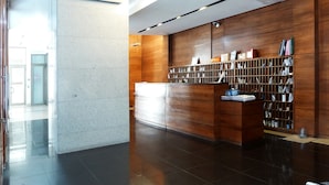 Ett modernt receptionsområde med en receptionsdisk i trä, en vit bardisk och en vägghängd bokhylla.