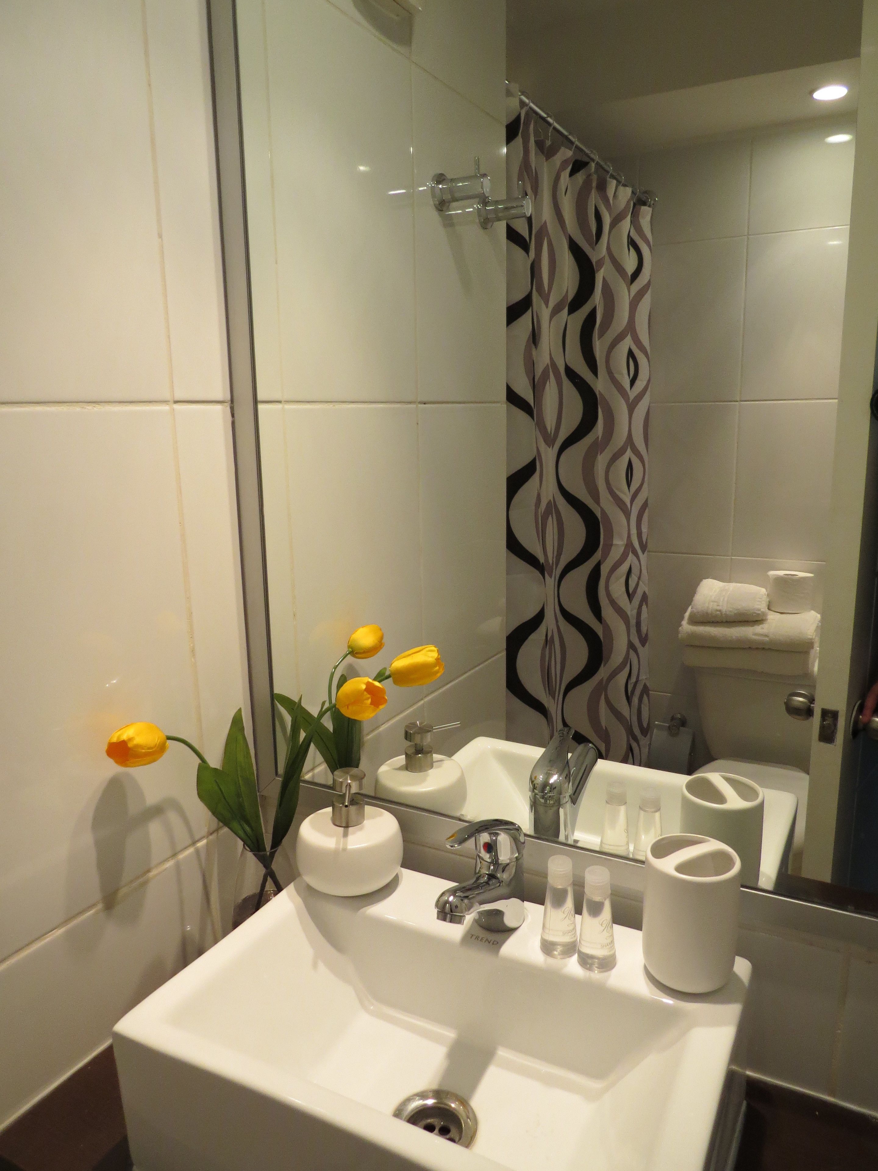 A bathroom with a white sink, mirror, and shower curtain.
