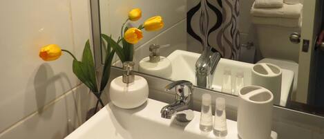 A bathroom with a white sink, mirror, and shower curtain.