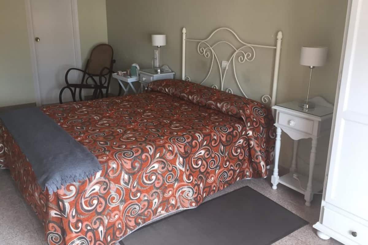 A bedroom with a bed, two bedside tables, a chair, and a desk.