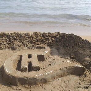 A sandy area with a large mound of earth and a circular pattern of stones. - Hostal Comercio (Denia)
