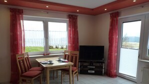 A dining area with a table, chairs, and a television. - Ferienwohnung Sauerlandblick (Korbach)