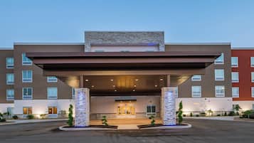 A modern hotel entrance with a covered driveway, multiple floors, and a stone facade.