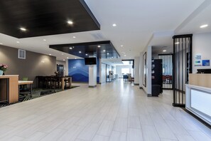 A hotel lobby with a reception desk, seating area, and a corridor leading to other rooms.