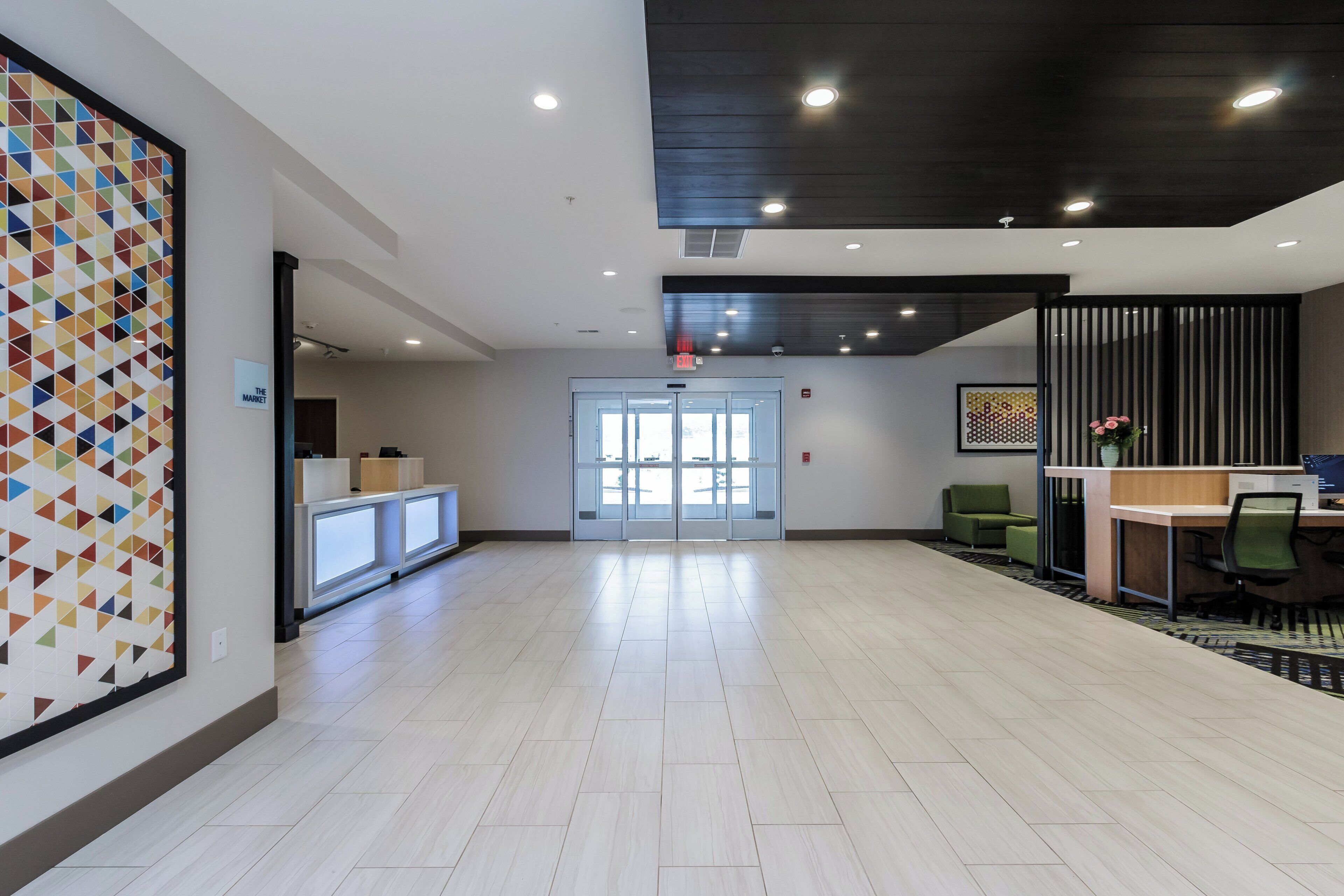 A spacious lobby with a reception desk, a patterned wall, and a modern ceiling design.