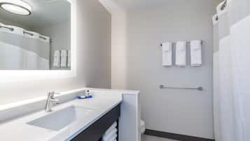 A modern bathroom with a large mirror, a sink, a towel rack, and a shower curtain.