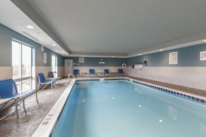 An indoor swimming pool with blue chairs and a lifeguard chair, a sign indicating a chemical storage area, and pool rules posted on the wall. - Holiday Inn Express & Suites - South Bend Casino  by IHG (South Bend)