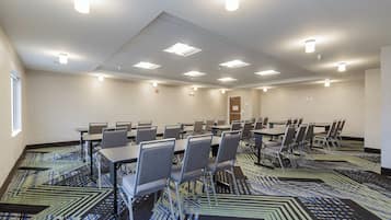 A conference room with multiple tables and chairs, a patterned carpet, and ceiling lights.