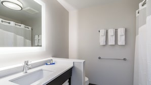 A modern bathroom with a large mirror, a sink, and a towel rack.