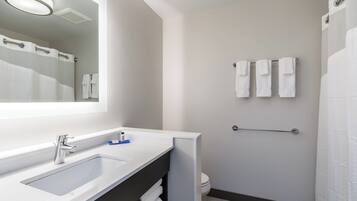 Un baño moderno con un espejo grande, un lavamanos y un perchero para toallas.