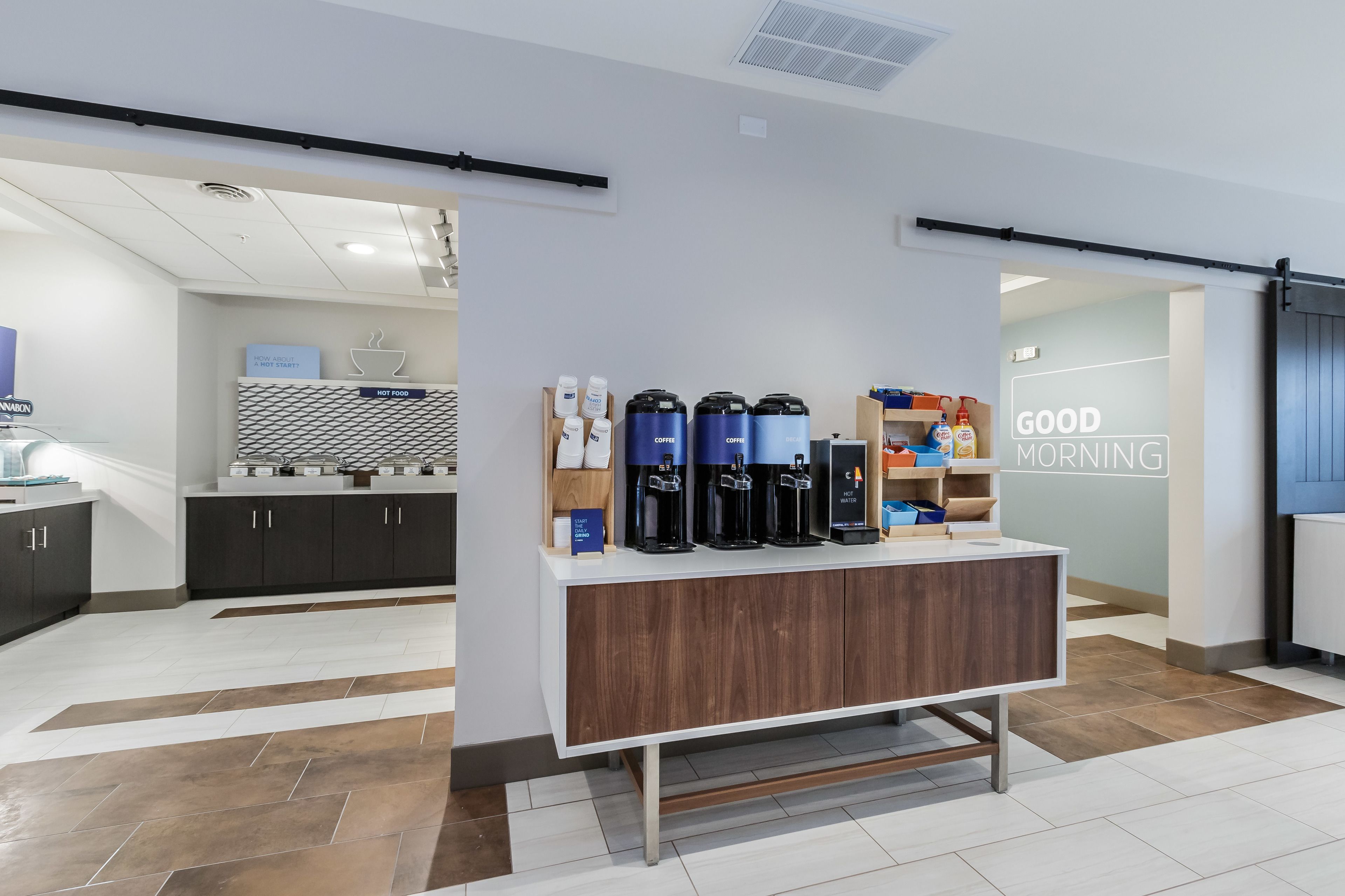 Een moderne koffiehoek met diverse koffiezetapparaten en een bord waarop staat 
