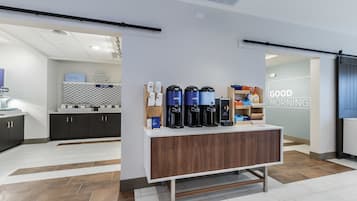 Een moderne koffiehoek met diverse koffiezetapparaten en een bord waarop staat