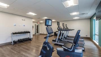 Een fitnessruimte met loopbanden, elliptische trainers en een dumbbellrek.