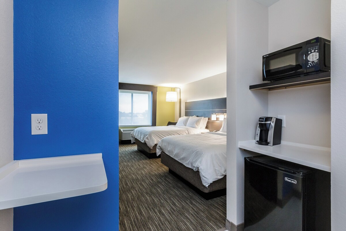A hotel room with a bed, a microwave, a coffee maker, and a window with a view.