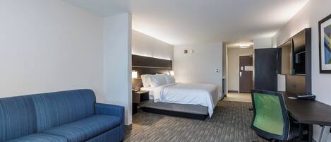 Een hotelkamer met een bed, een bureau, een stoel, een bank en een televisie.