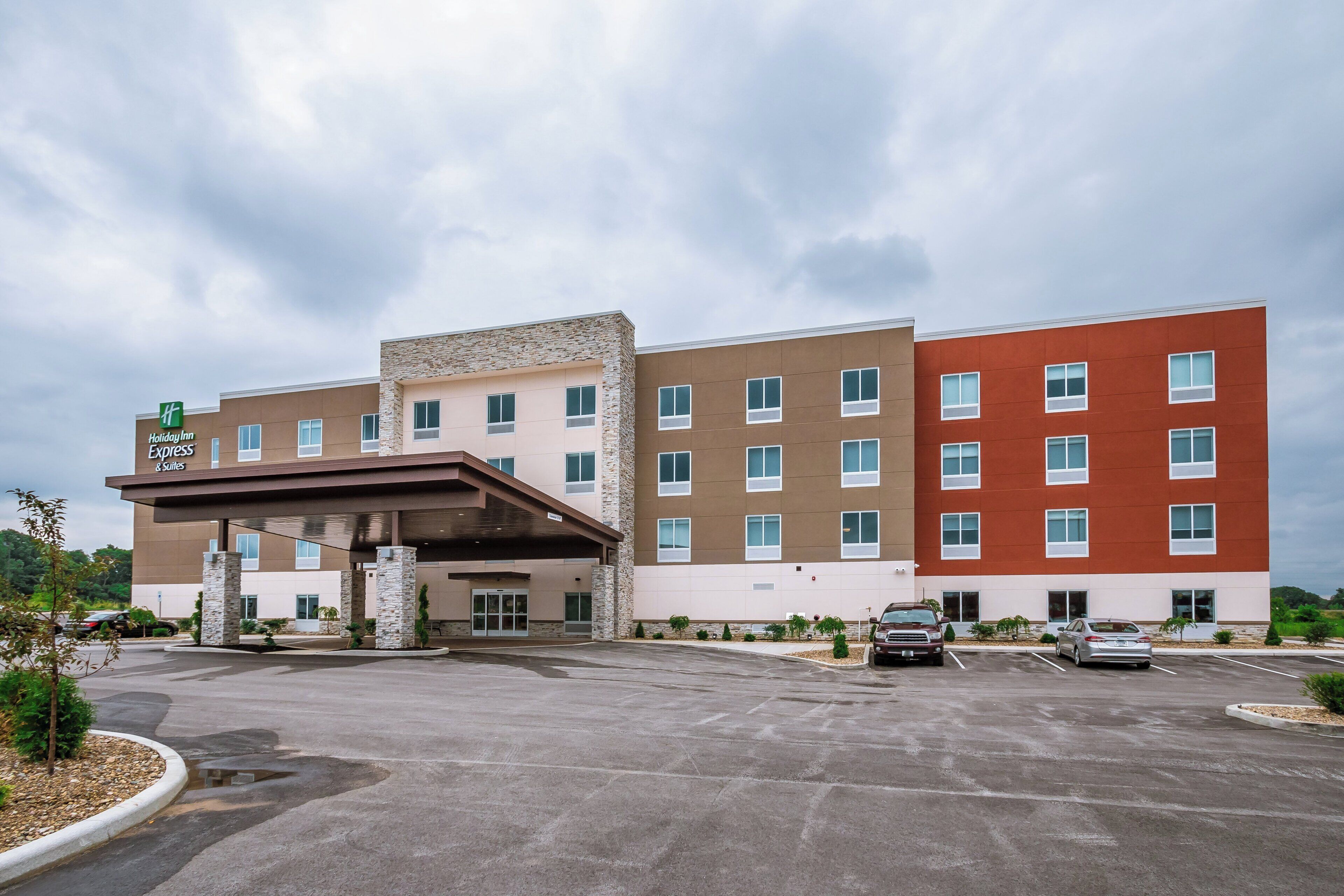 A Holiday Inn Express & Suites building with a covered entrance, multiple floors, and a parking lot.